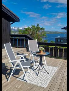 two chairs and a table on a deck at Northern lights central apartment in Harstad