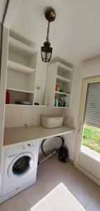 a laundry room with a washing machine and a window at La maison de Coq-licot ! in Salignac Eyvigues