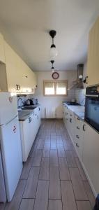a kitchen with white appliances and a wooden floor at La maison de Coq-licot ! in Salignac Eyvigues