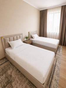 two beds in a hotel room with white sheets at Datka Hotel in Bishkek