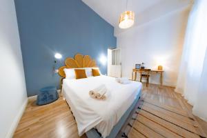 a bedroom with a large white bed with two slippers at Inderooms Carloforte in Carloforte