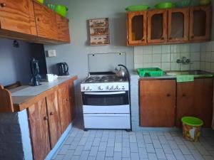 a kitchen with a white stove and wooden cabinets at Over the Rainbow Guest House in Hibberdene
