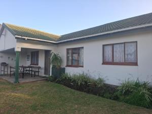 a white house with a table in the yard at Over the Rainbow Guest House in Hibberdene