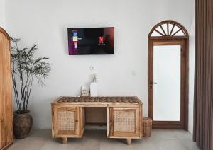 a room with a table and a tv on the wall at La PAYANA House Penida in Nusa Penida