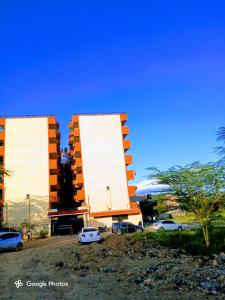 two large buildings with cars parked in a parking lot at Open Haven One Bedroom Apartments in Ongata Rongai 