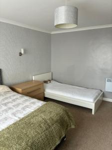 a bedroom with two beds and a table and a lamp at Esplanade Court Apartment with communal seasonal heated pool in Paignton