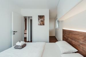 a bedroom with a white bed with a wooden headboard at Modern Seaside House in Pakoštane