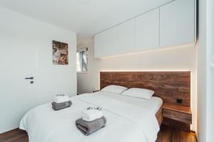 two beds in a bedroom with white walls and wood at Modern Seaside House in Pakoštane