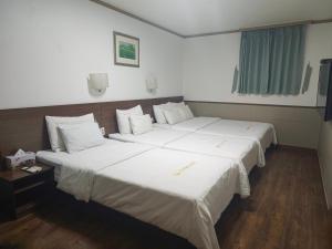 two beds in a hotel room with white sheets at 글로벌인 동대문 시티데이즈 인 호텔 in Seoul