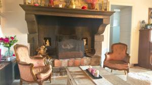 a living room with two chairs and a fireplace at La Petite Maison - 4 voyageurs in Voudenay-lʼEglise