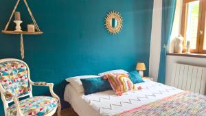 a blue bedroom with a bed and a chair at La Petite Maison - 4 voyageurs in Voudenay-lʼEglise