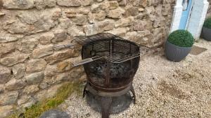 a charcoal grill in front of a stone wall at La Petite Maison - 4 voyageurs in Voudenay-lʼEglise +21 photos
