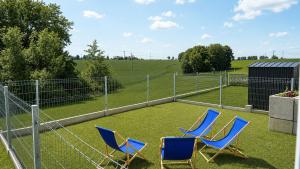 two blue chairs in a field with a fence at Serce Kotliny Kłodzkiej - Apartament 54m2 - 3 pokoje, balkon, ogródek in Kłodzko