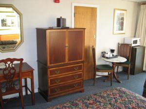a bedroom with a large wooden dresser and a desk and a table at Sea Whale Motel in Middletown