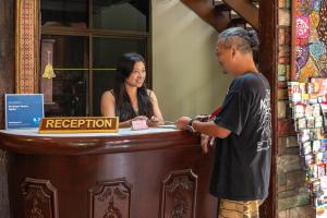 a man and a woman standing at a register at Boutique House Nipha in Chiang Mai