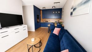 a living room with a blue couch and a kitchen at Serce Kotliny Kłodzkiej - Apartament 54m2 - 3 pokoje, balkon, ogródek in Kłodzko +28 photos