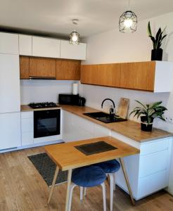 a kitchen with white cabinets and a wooden table at Studio Park Śląski m.10 Katowice/Chorzów in Chorzów