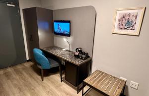 a room with a desk and a blue chair at THE Pretoria Hotel in Pretoria