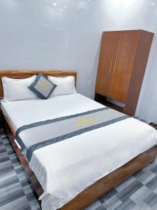 a bedroom with a bed and a wooden cabinet at Hotel Nắng Hạ in Chú Cư
