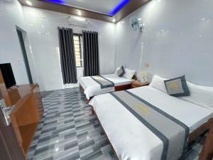 a hotel room with two beds and a television at Hotel Nắng Hạ in Chú Cư