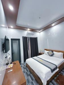 a bedroom with a large bed and a wooden desk at Hotel Nắng Hạ in Chú Cư