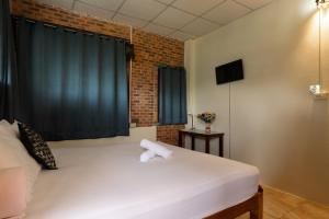 a bedroom with a white bed with a brick wall at Boutique House Nipha in Chiang Mai