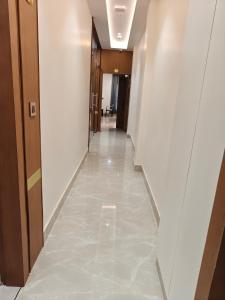 a hallway in a building with white walls and a tile floor at Hotel ROYAL DC in Alīgarh