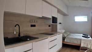 a kitchen with white cabinets and a sink and a bed at Tiny House Krumlov, Terrace, Parking in Český Krumlov +18 photos