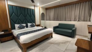 a bedroom with a bed and a green chair at Mojo stay hotel in Ahmedabad