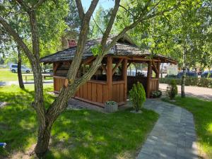 a wooden gazebo in a park with a tree at Apartamenty Sznurki in Sznurki