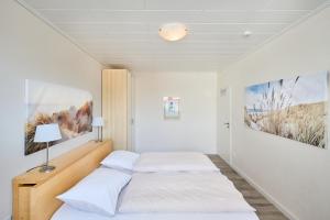 two beds in a room with white walls at Haus Schildt, FeWo 8 in Duhnen +8 photos