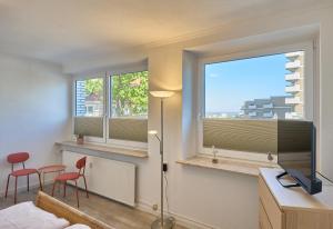 a living room with two windows and a television at Haus Schildt, FeWo 8 in Duhnen