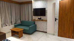 a living room with a green chair and a tv at Mojo stay hotel in Ahmedabad