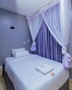 a bedroom with a white bed with purple curtains at The VIP Luxury CBD in Kisumu