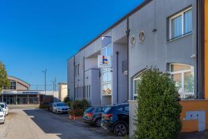 a building with cars parked in a parking lot at Hotel Rubicone in Savignano sul Rubicone