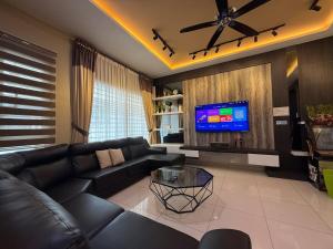 a living room with a black couch and a tv at Seri Botani Private Pool Villa 5BR in Ipoh