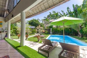 a patio with an umbrella and chairs and a swimming pool at Villa Raquel by Betterplace in Seminyak
