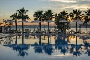 a swimming pool with umbrellas and tables and the ocean at The Komana Dardanelles in Hamidiye