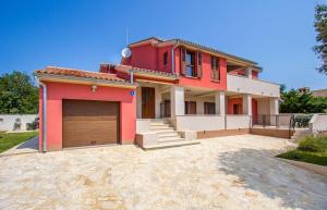 a red house with a garage in front of it at Apartments Racchi in Banjole