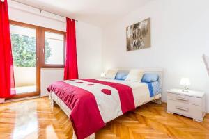 a bedroom with a large bed with red curtains at Apartments Racchi in Banjole