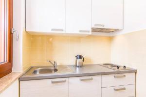 a kitchen with a sink and white cabinets at Apartments Racchi in Banjole +25 photos
