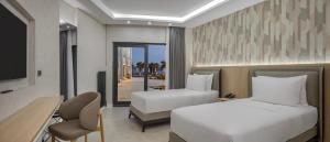 a hotel room with two beds and a desk and a television at The Komana Dardanelles in Hamidiye +16 photos