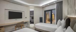 a hotel room with a bed and a flat screen tv at The Komana Dardanelles in Hamidiye