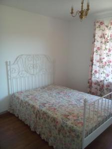 a bedroom with a white bed with a floral bedspread at Sea Apartment in Liepāja