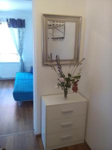 a dresser with a mirror and a vase with flowers on it at Sea Apartment in Liepāja