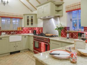 a kitchen with green cabinets and a red stove top oven at Lavender Cottage - Ukc9687 in Thorndon
