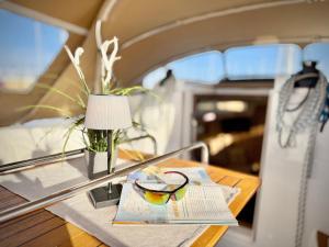 a table with a lamp and a book and glasses at Hausboot Segelyacht Nui in Burgtiefe auf Fehmarn 