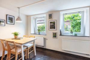 a dining room with a table and chairs and two windows at Ferienwohnung am Eichhölzle in Wehr