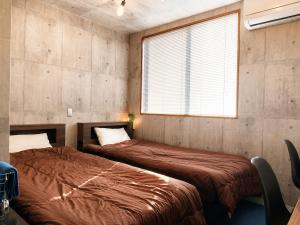 two beds sitting in a room with a window at 江田島BASE in Okimi in Etajima