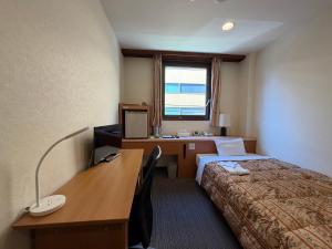 una camera d'albergo con un letto e una scrivania con un computer di Hotel Ikeda a Nagasaki
